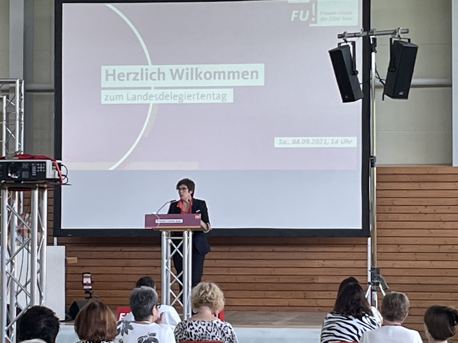 Rednerin am Podium mit PA-Lautsprechern